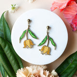 Pair of earrings on a white plate with flowers and leaves around