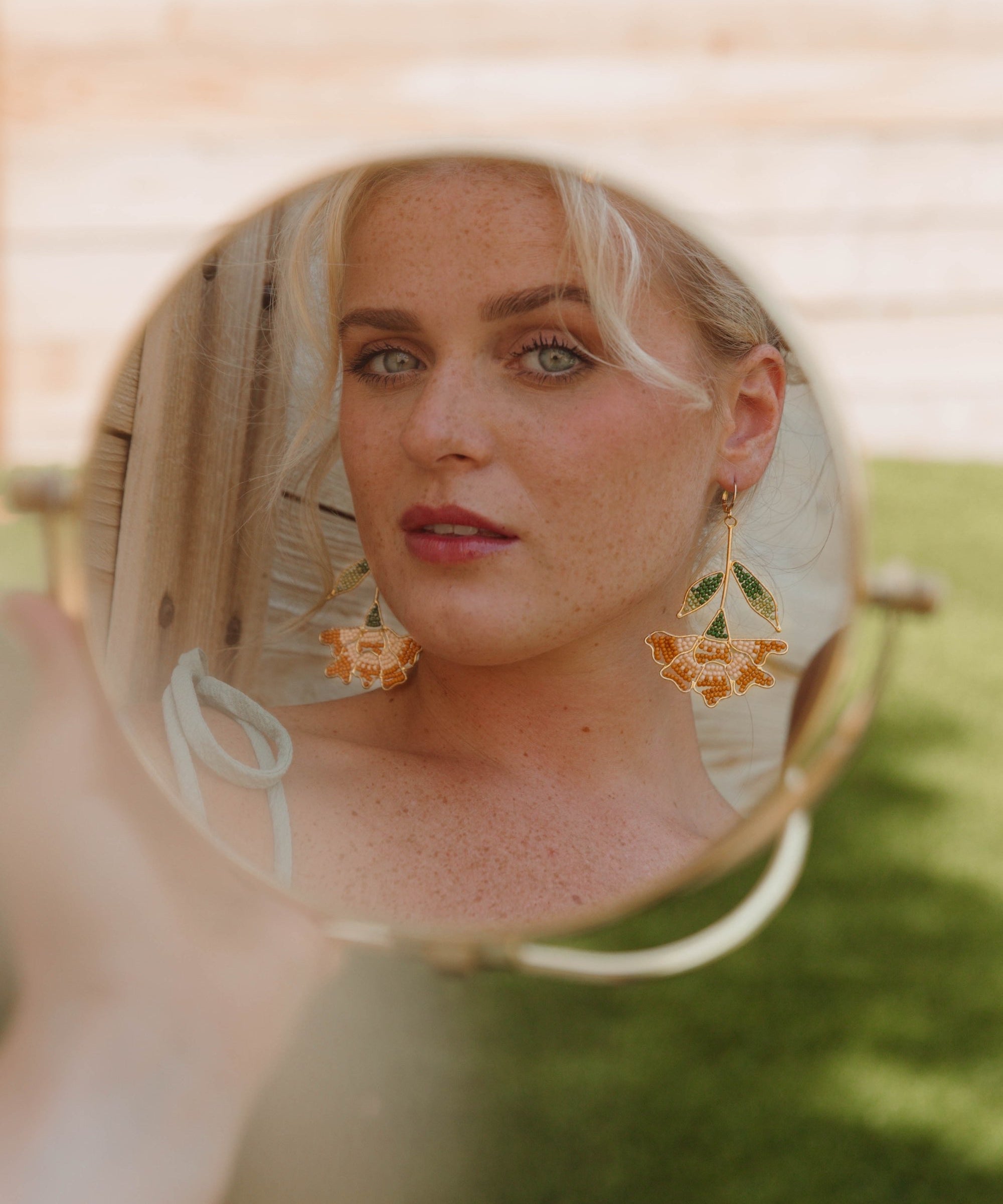 Woman wearing floral earrings with a blurred background